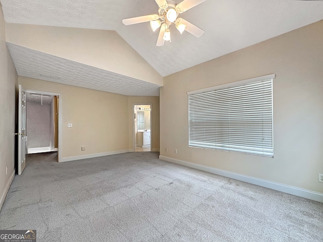 unfurnished room with carpet, ceiling fan, vaulted ceiling, and a textured ceiling