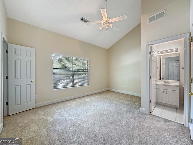 unfurnished bedroom featuring ensuite bathroom, sink, high vaulted ceiling, light carpet, and ceiling fan