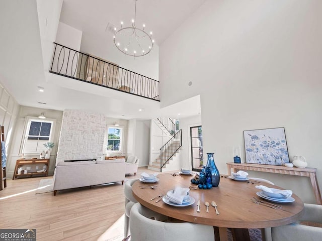 dining room featuring a towering ceiling, wood-type flooring, and a chandelier