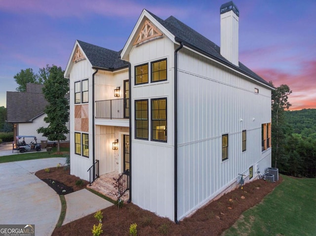 property exterior at dusk featuring a balcony and cooling unit