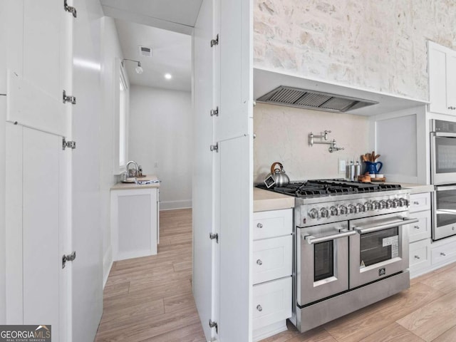 kitchen with white cabinetry, light hardwood / wood-style flooring, and appliances with stainless steel finishes