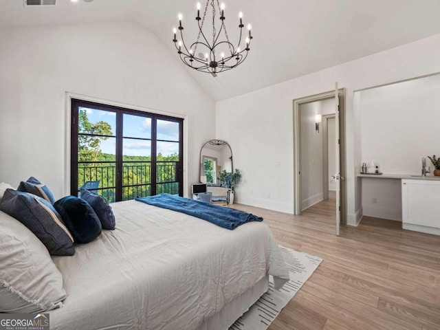 bedroom with light hardwood / wood-style flooring, an inviting chandelier, access to outside, sink, and high vaulted ceiling