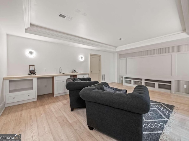 living room featuring a raised ceiling, light hardwood / wood-style flooring, and ornamental molding