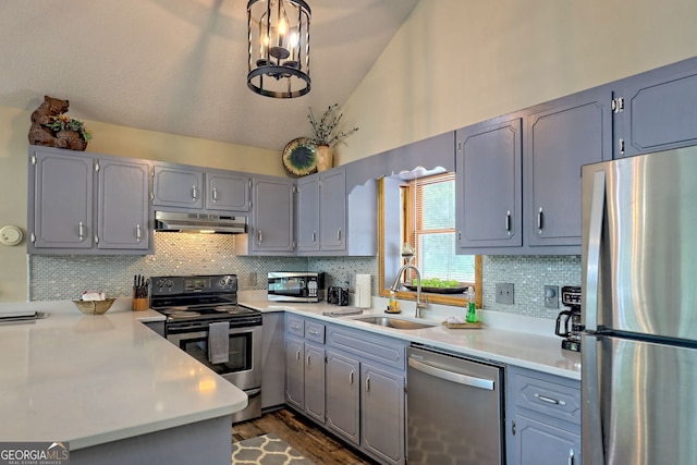 kitchen featuring stainless steel appliances, sink, vaulted ceiling, decorative backsplash, and pendant lighting