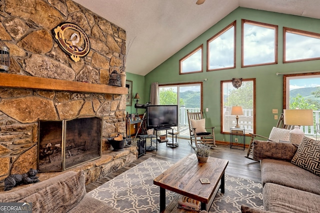 living room featuring hardwood / wood-style flooring, high vaulted ceiling, and a stone fireplace