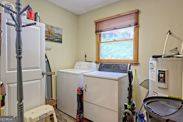 laundry room featuring electric water heater, washer and dryer, and wood-type flooring