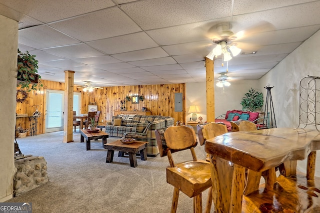 living room featuring carpet flooring, wood walls, and ceiling fan