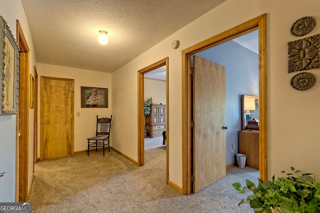 hallway with a textured ceiling and light colored carpet