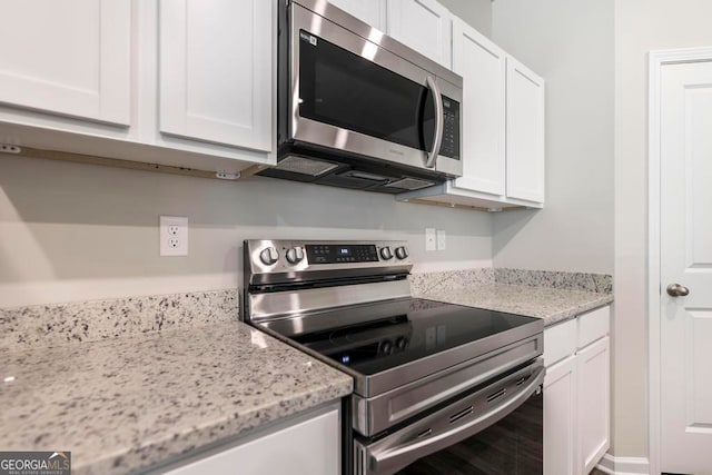 kitchen featuring light stone countertops, white cabinets, and stainless steel appliances