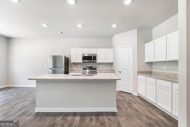 kitchen featuring white cabinetry, stainless steel appliances, hardwood / wood-style floors, and an island with sink