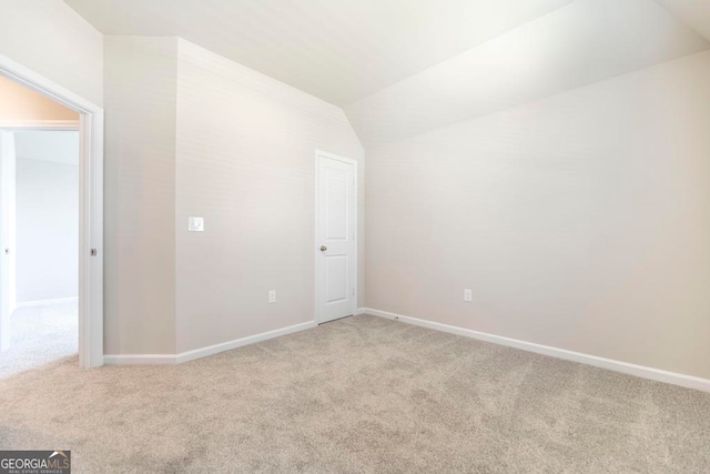 carpeted empty room with lofted ceiling