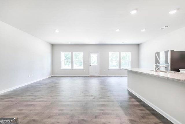 unfurnished living room with sink, a wealth of natural light, and wood-type flooring