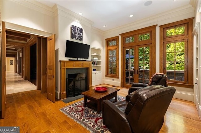 living room with built in shelves, french doors, light hardwood / wood-style floors, and ornamental molding