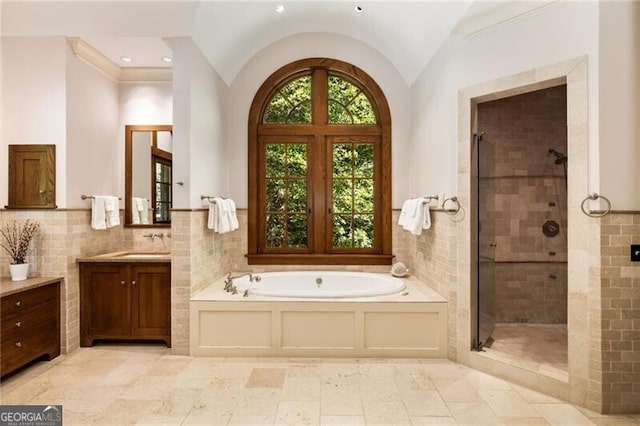 bathroom featuring separate shower and tub, tile walls, vanity, and lofted ceiling