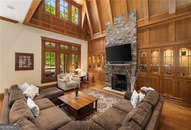 living room with wood walls, a fireplace, wood-type flooring, and a high ceiling