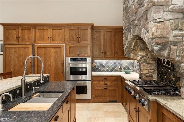 kitchen with decorative backsplash, appliances with stainless steel finishes, dark stone counters, and sink