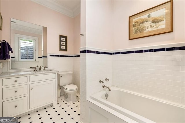 bathroom with vanity, a bathing tub, toilet, ornamental molding, and tile walls