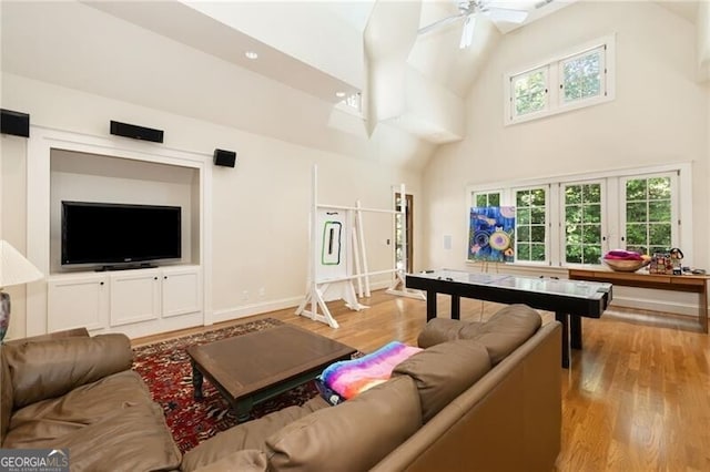 living room featuring ceiling fan, high vaulted ceiling, and light hardwood / wood-style floors