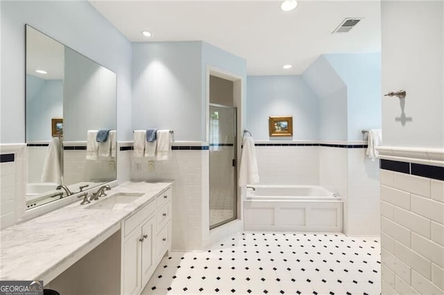 bathroom with tile patterned floors, plus walk in shower, vanity, and tile walls