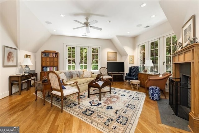 living room featuring ceiling fan, vaulted ceiling, light hardwood / wood-style flooring, and french doors