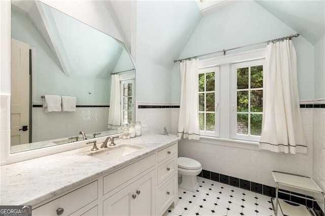 bathroom featuring vanity, toilet, lofted ceiling, and tile walls