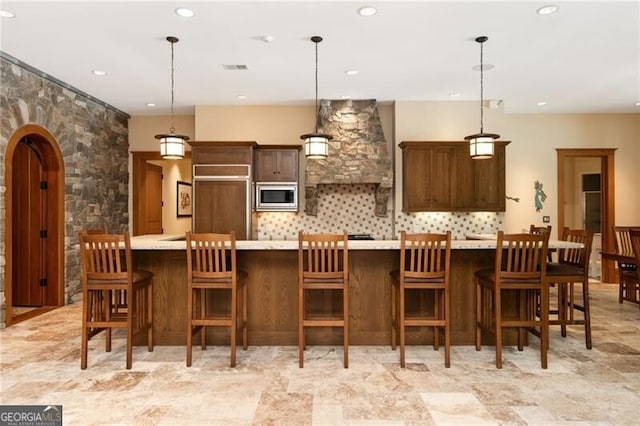 kitchen featuring a kitchen breakfast bar, built in appliances, a large island, and pendant lighting