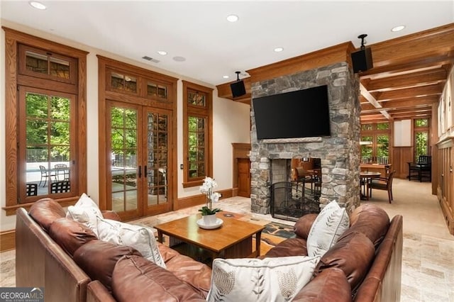 living room featuring a stone fireplace and french doors