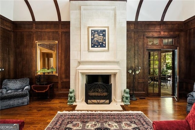 living area featuring french doors, dark hardwood / wood-style floors, and wooden walls