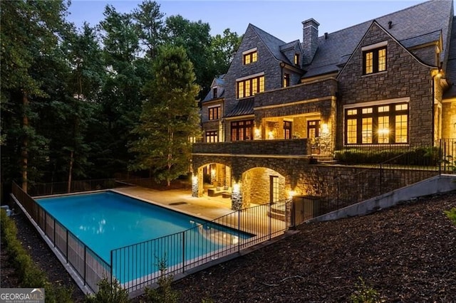 pool at dusk with a patio area