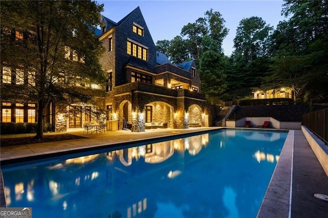 pool at dusk featuring a patio area