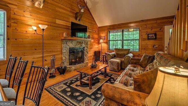 living room featuring lofted ceiling, hardwood / wood-style floors, a fireplace, and wooden walls