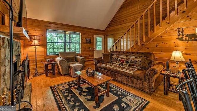 living room with wooden walls, lofted ceiling, and light wood-type flooring