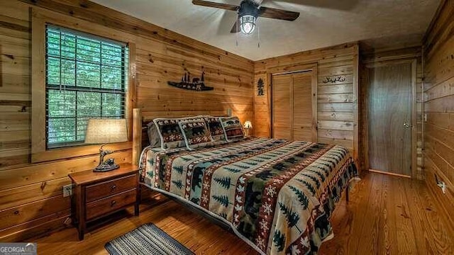 bedroom with hardwood / wood-style flooring, wood walls, and multiple windows