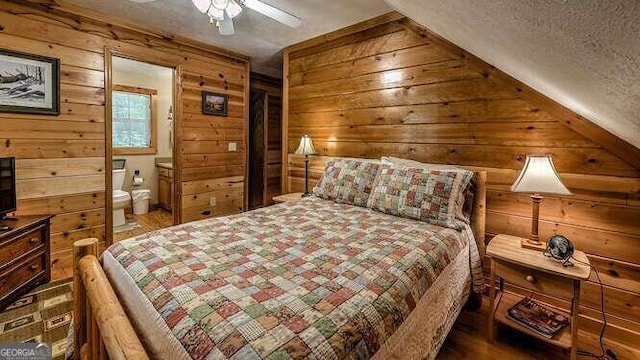 bedroom with hardwood / wood-style floors, ceiling fan, a textured ceiling, connected bathroom, and wooden walls