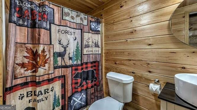 bathroom featuring vanity, toilet, wood walls, and a shower with curtain