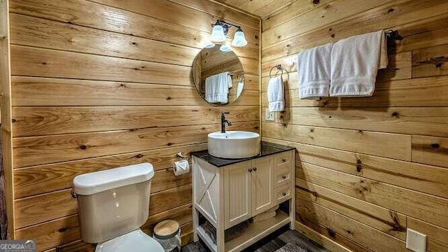 bathroom with vanity, wood walls, and toilet