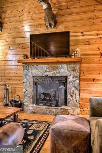 sitting room with a stone fireplace and wooden walls