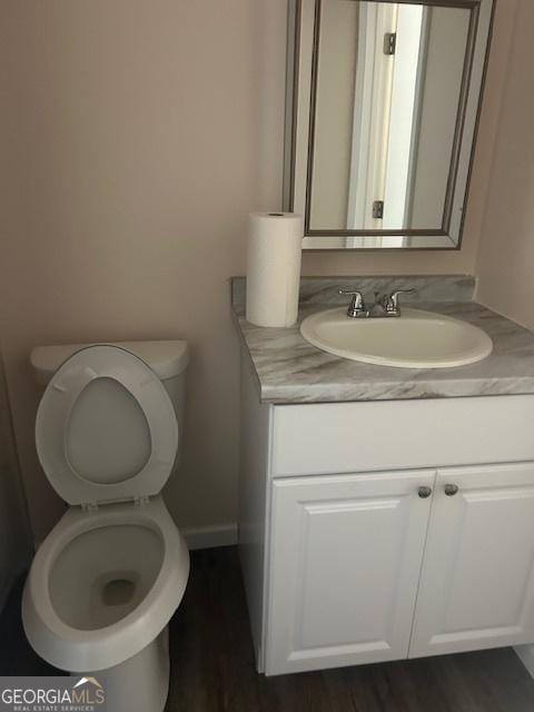 bathroom with hardwood / wood-style flooring, vanity, and toilet