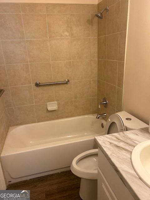 full bathroom featuring vanity, wood-type flooring, tiled shower / bath combo, and toilet