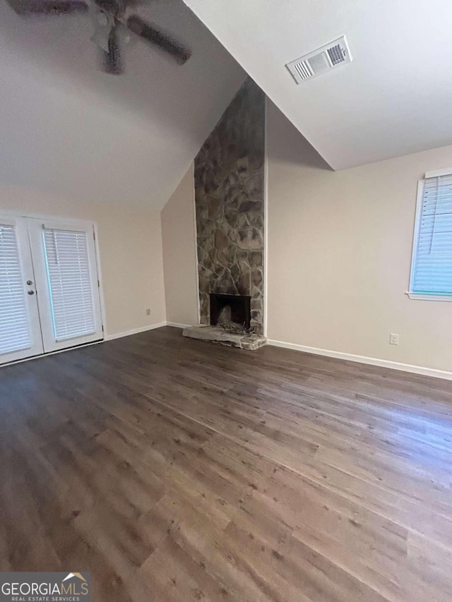 unfurnished living room featuring a stone fireplace, ceiling fan, wood-type flooring, and vaulted ceiling