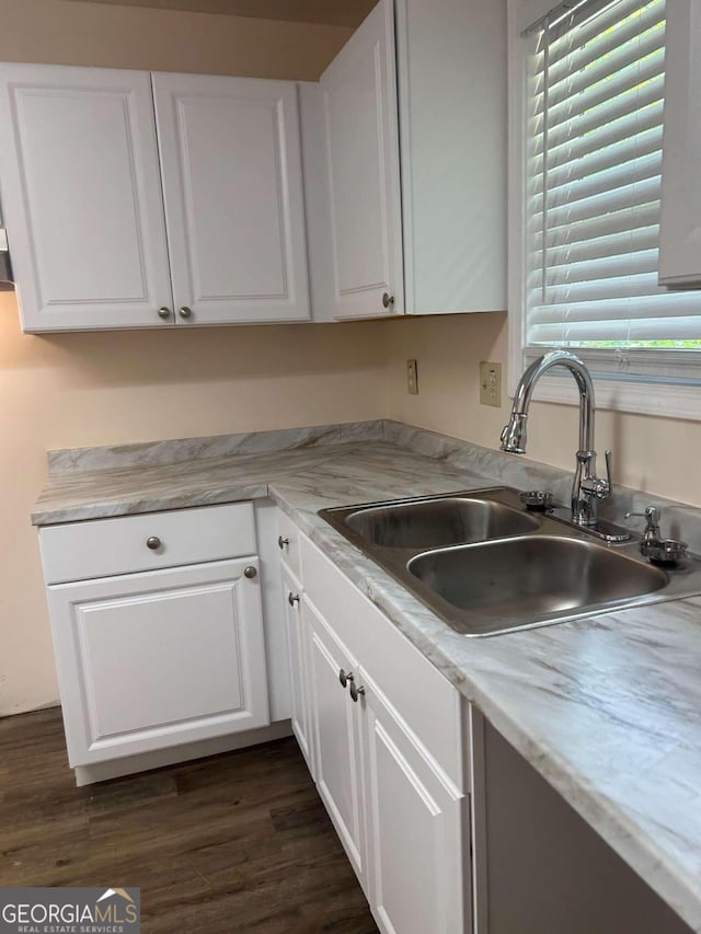 kitchen with white cabinets, light stone counters, sink, and dark wood-type flooring