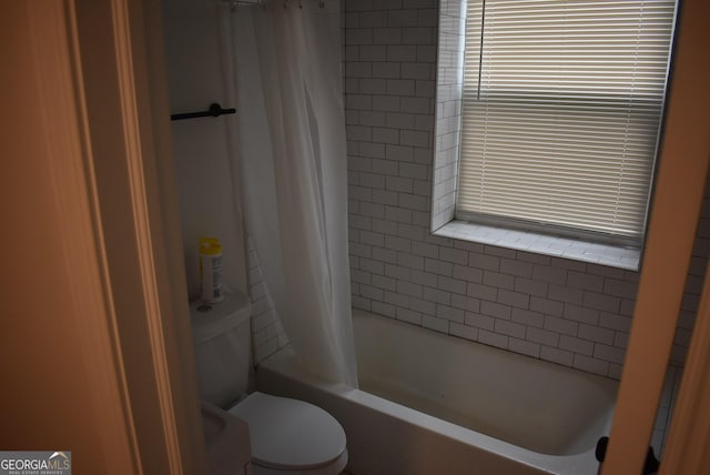 bathroom featuring shower / bathtub combination with curtain and toilet