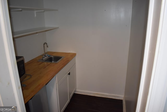 bar with sink, white cabinets, and wood counters