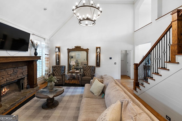 living room featuring hardwood / wood-style floors, a stone fireplace, high vaulted ceiling, and a chandelier