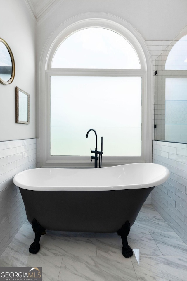 bathroom with a bathing tub, tile walls, and a wealth of natural light