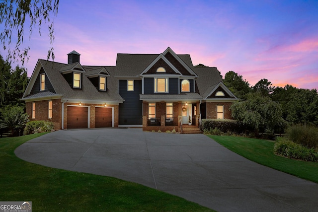 view of front of house featuring a garage, a lawn, and covered porch