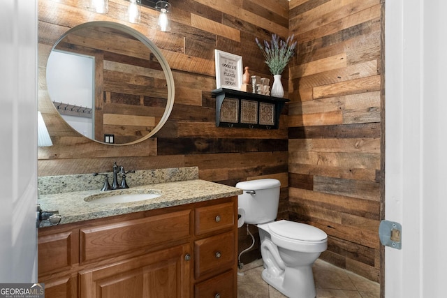 bathroom with vanity, tile patterned flooring, wooden walls, and toilet