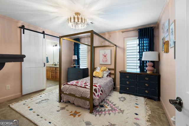 bedroom with crown molding, ensuite bath, a chandelier, carpet floors, and a barn door