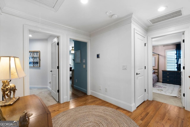 hallway featuring crown molding and light hardwood / wood-style flooring