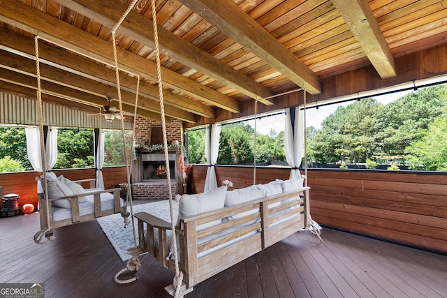 wooden terrace with ceiling fan and an outdoor living space with a fireplace